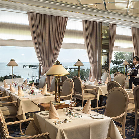 Elegant restaurant with sea view and set tables at Maritim Seehotel Timmendorfer Strand.