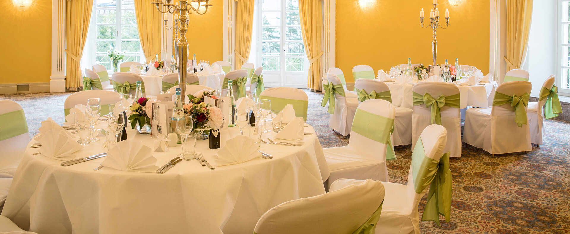 Fürst-Karl-Kuppelsaal Banquet hall with white covers and green bows for weddings at Maritim Hotel Bad Wildungen