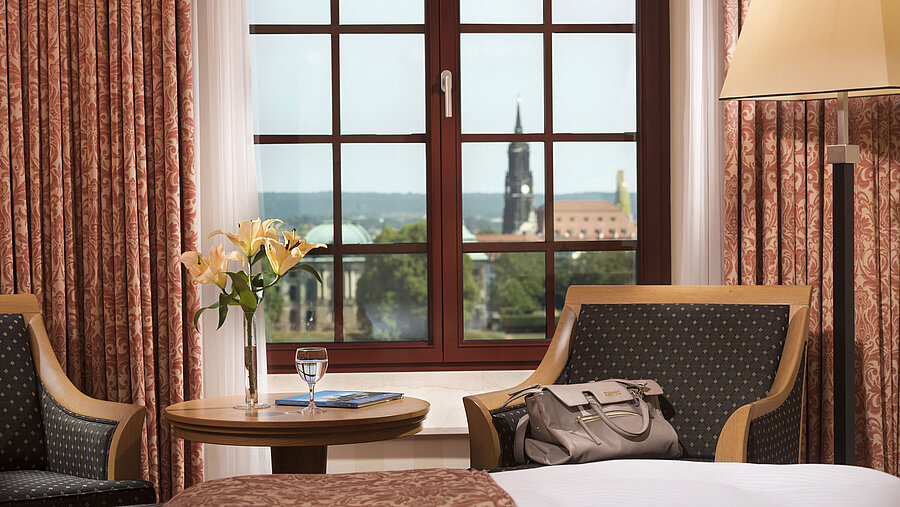 Seating area in the Superior room at Maritim Hotel Dresden with a window view of the historic old town.