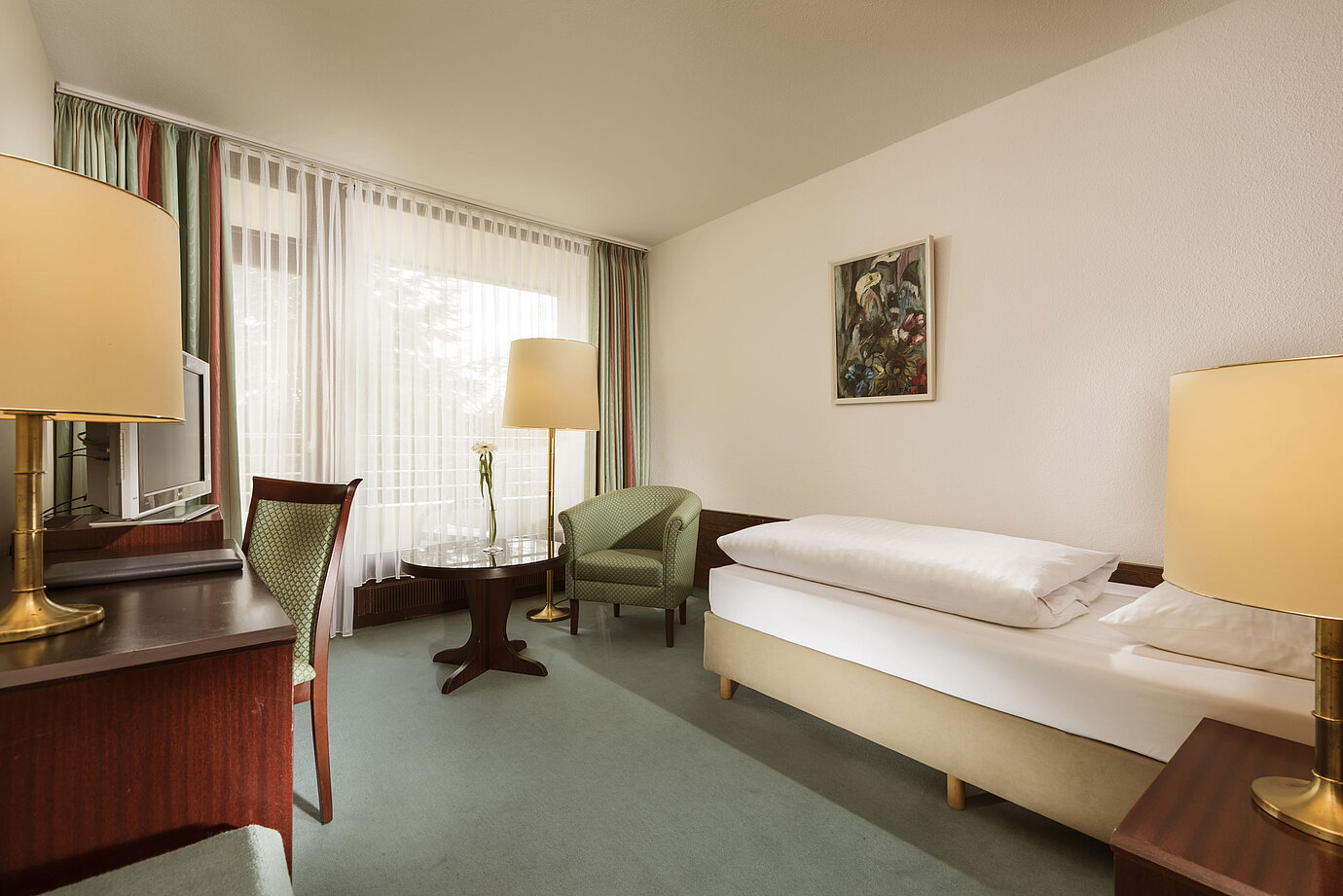 Bright single room with armchair, desk and large window at Maritim Hotel Bad Salzuflen
