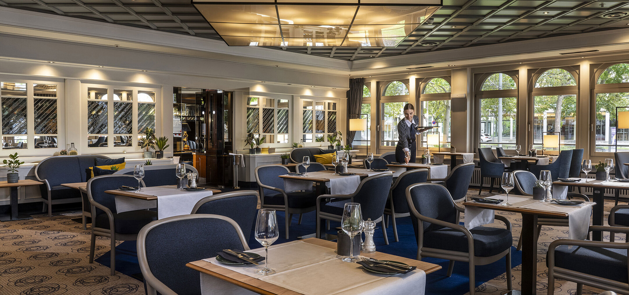 Restaurant Modern restaurant at Maritim Hotel Darmstadt with set tables and elegant design. A staff member is providing service.