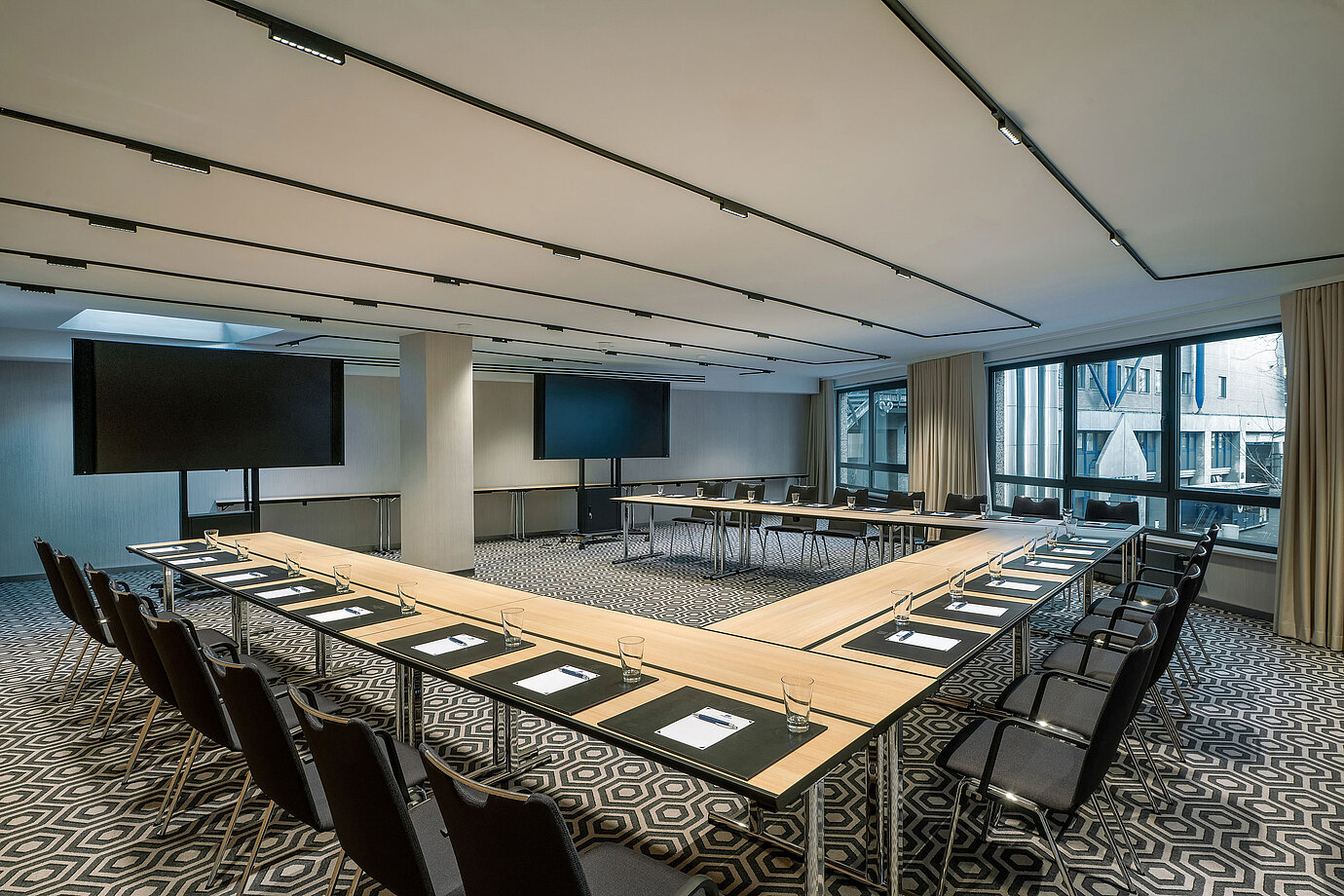 Meeting room 1 with U-shaped seating, conference tables, modern media technology and a bright interior.