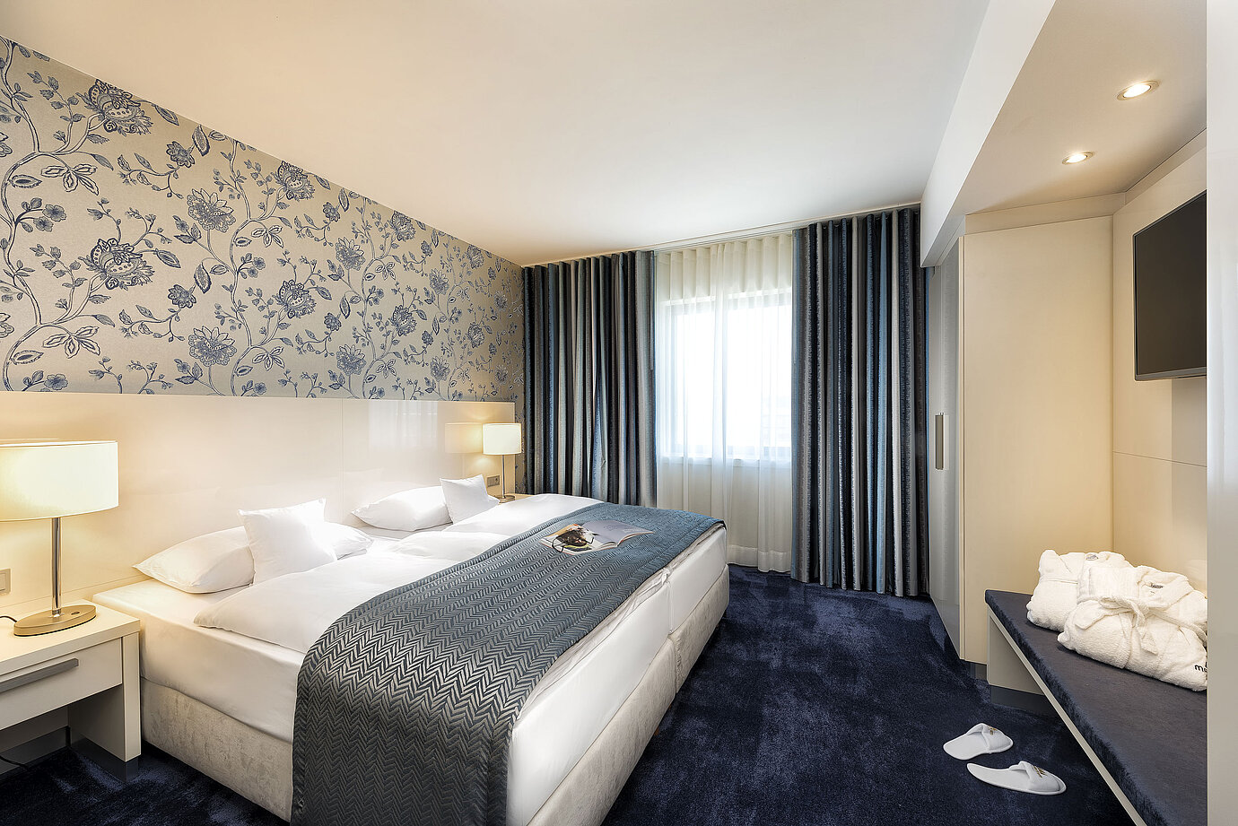 Elegant suite at Maritim Hotel Bonn with a large bed, blue bedspread, and stylish decor.