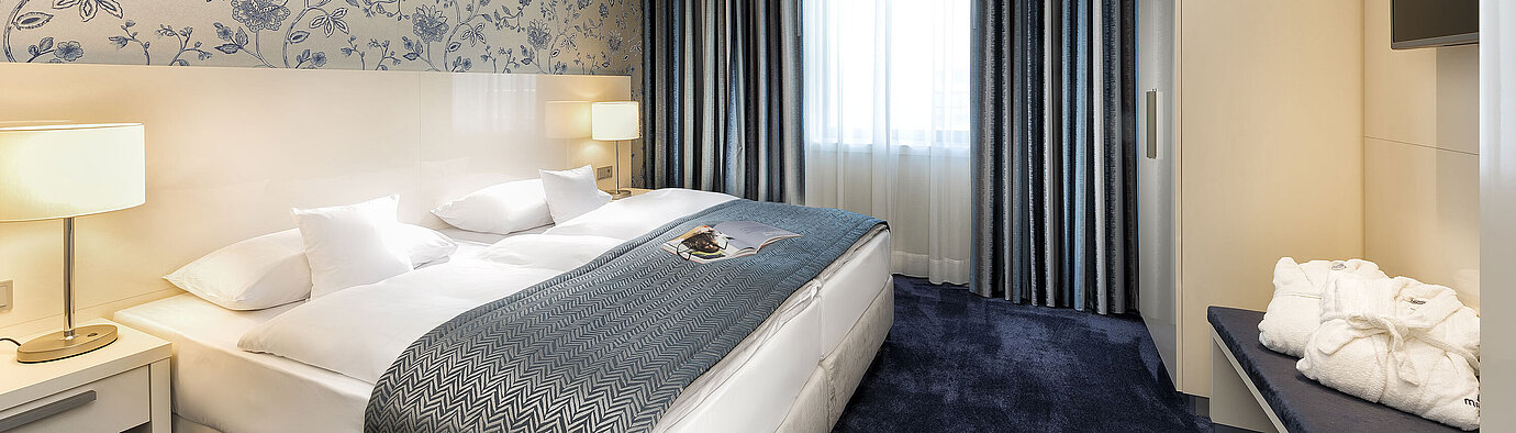 Elegant suite at Maritim Hotel Bonn with a large bed, blue bedspread, and stylish decor.