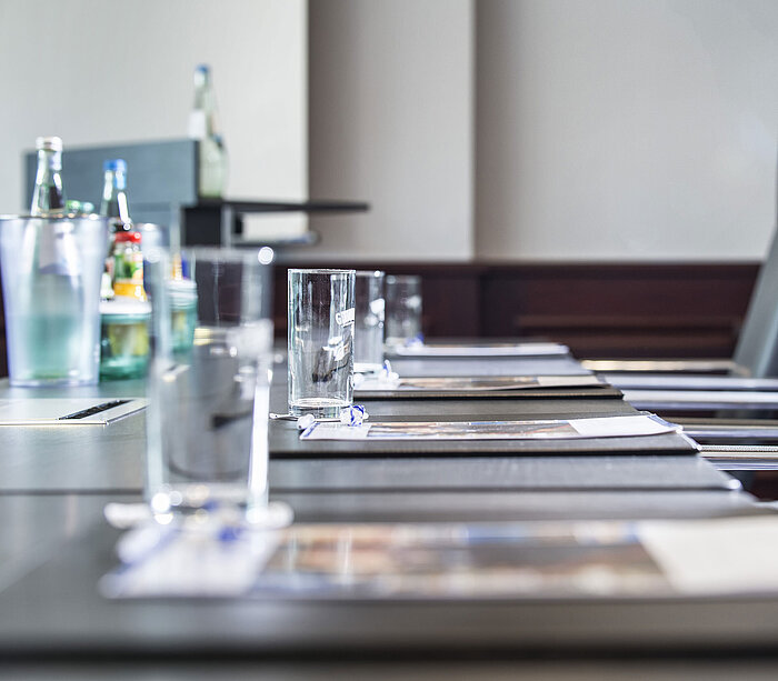 Close-up of a stylishly set conference table with glasses and writing pads at Maritim Hotel Hannover.