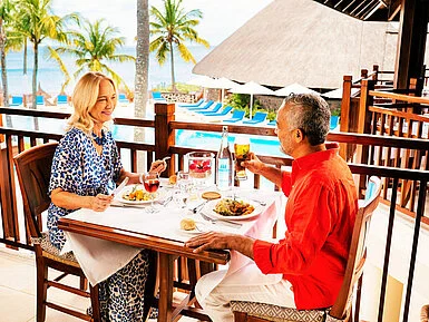 Restaurant Belle Vue Couple enjoying a relaxed meal overlooking pool, palm trees and sea