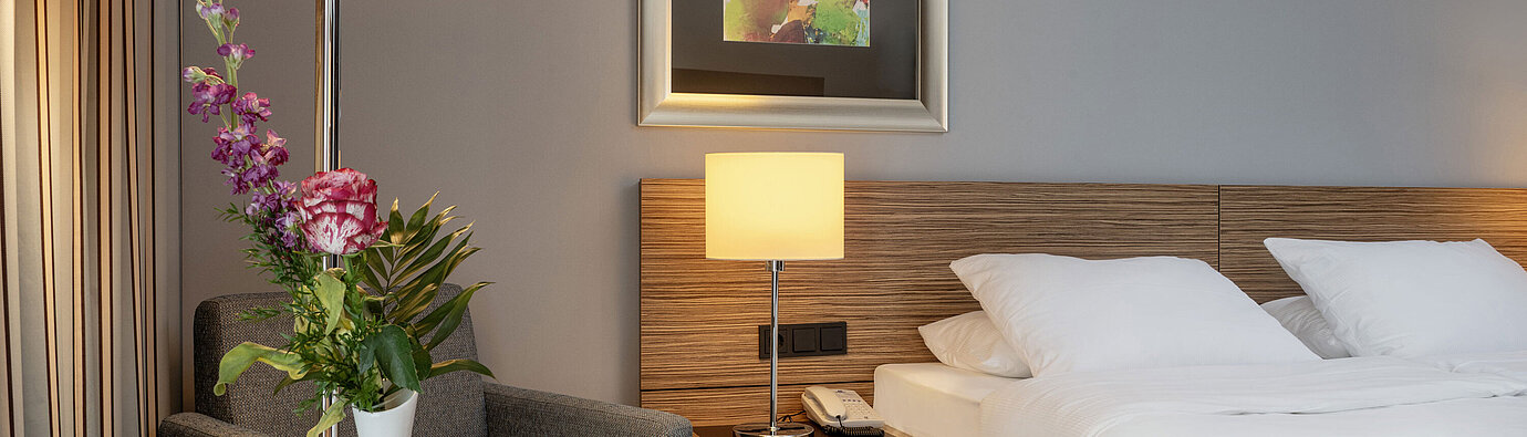 Cozy seating area with a flower vase next to the comfortable bed in the Superior Room at Maritim Hotel Darmstadt