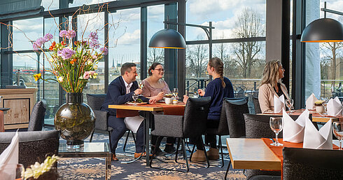 Guests enjoying a meal in the restaurant at Maritim Hotel Dresden with outdoor views.