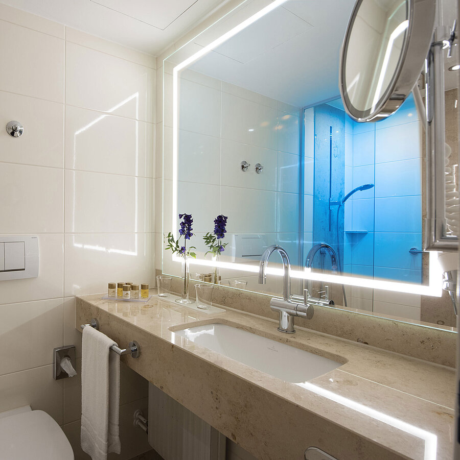 Bright bathroom with large mirror and amenities at Maritim Hotel Titisee
