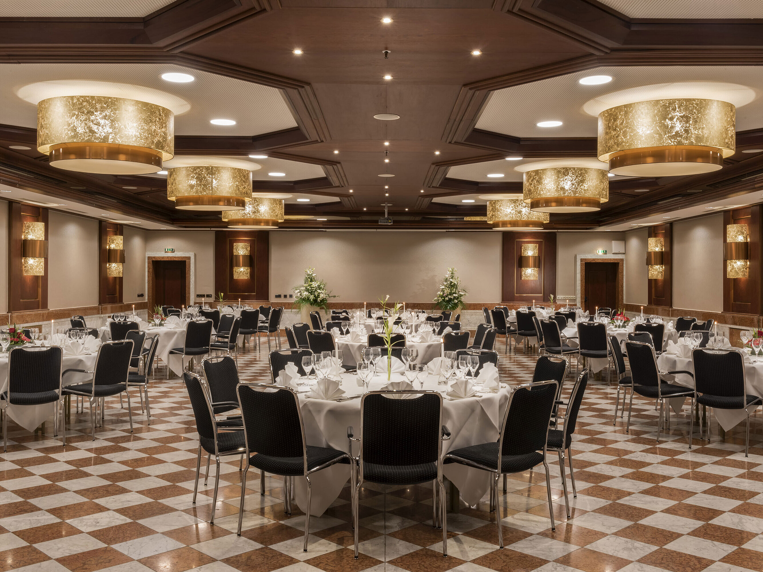 Elegant banquet hall at Maritim Hotel Königswinter with round tables, stylish decor, and chandeliers.