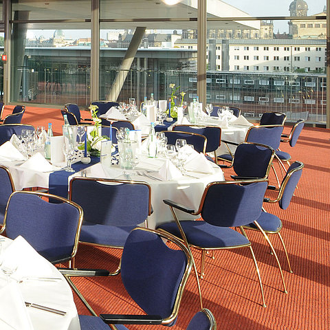 Elegant event hall in Maritim Hotel Dresden with festively set tables and a view of the city.