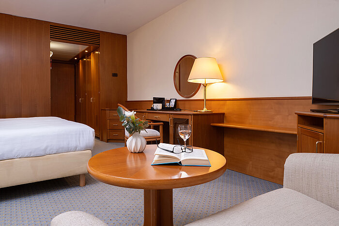 Classic double room with double bed, desk, TV, seating area and warm lighting for a relaxing stay.