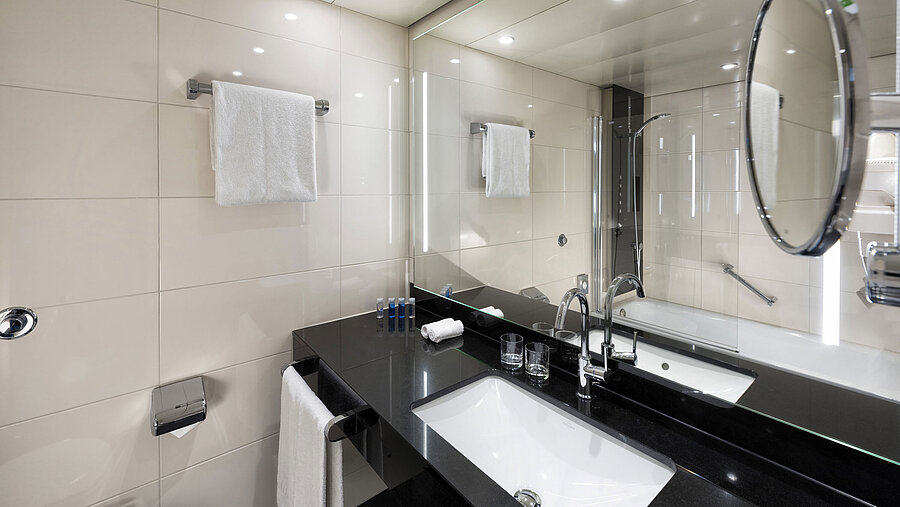 Modern bathroom at Maritim Hotel Ulm with a bathtub and stylish lighting.