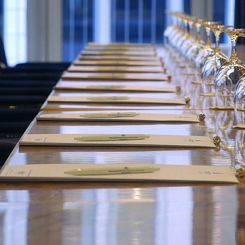 Close-up of a prepared conference table at Maritim proArte Hotel Berlin, with notebooks and wine glasses.