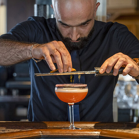 Bartender refining a cocktail at the bar of the Maritim Hotel Würzburg.