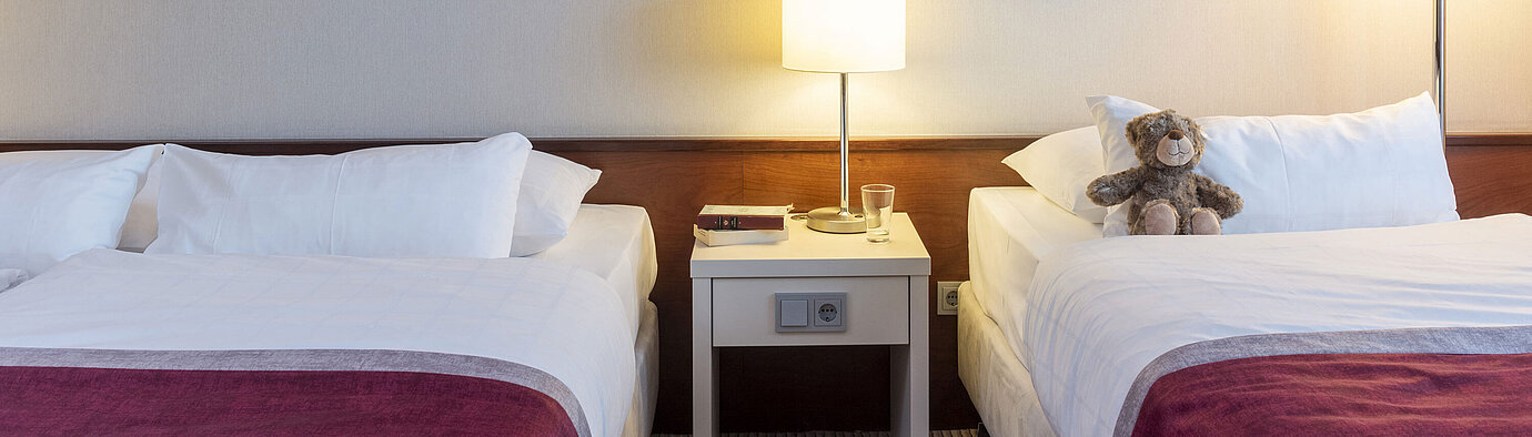 Classic family room at Maritim Hotel Bonn with two beds, bedside table, and modern art for a comfortable stay.