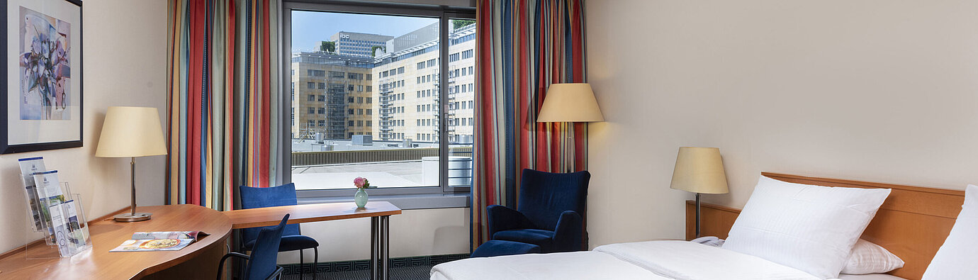 Classic room at Maritim Hotel Frankfurt with a cozy double bed, desk, and city view.