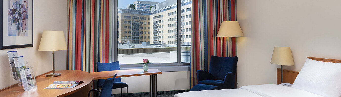 Classic room at Maritim Hotel Frankfurt with a cozy double bed, desk, and city view.