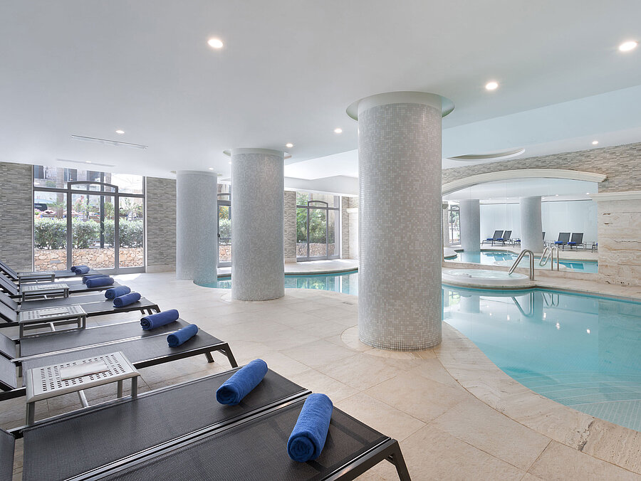 Indoor Pool Modern indoor pool with sun loungers and towels at the spa of Maritim Antonine Hotel & Spa Malta for relaxing wellness moments.