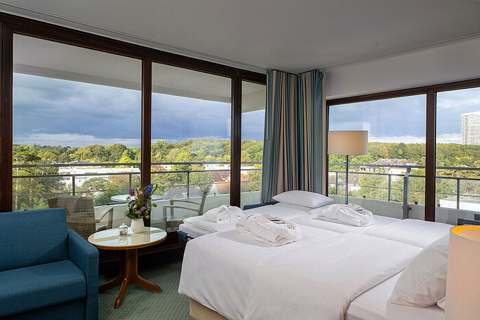 SuperiorPlus Family room facing the park with double bed, seating area and large windows overlooking the greenery