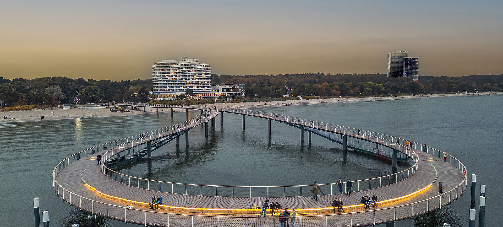 Illuminated pier at dusk in front of the Maritim Seehotel Timmendorfer Strand.