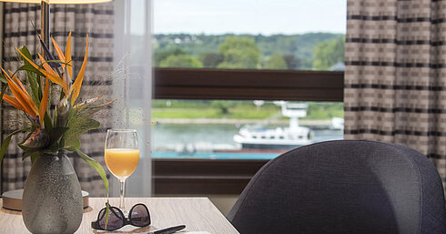 Table decoration at Maritim Hotel Königswinter with fresh flowers, drink, and Rhine view.