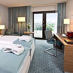 Superior room at Maritim Hotel Darmstadt featuring stylish design, desk, cozy seating area, and double bed with bathrobes.