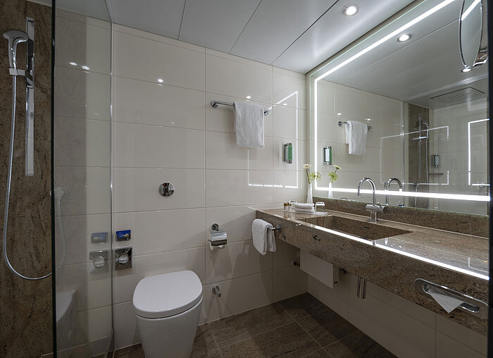 Comfort Bathroom Modern bathroom at the Maritim Hotel Bremen with luxurious fixtures, large illuminated mirror, and walk-in shower.