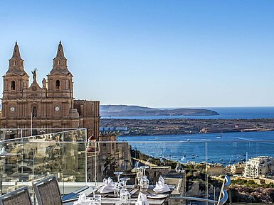 Sea view from the terrace Rooftop restaurant with set tables, views of church, coastline and blue Mediterranean Sea