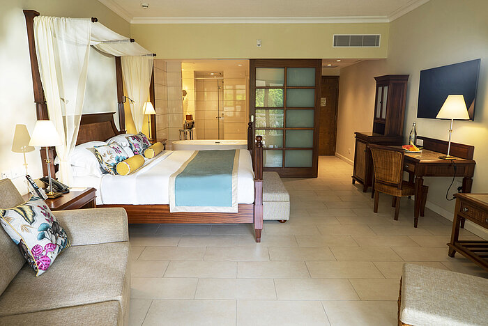 Spacious hotel room with double bed, desk and open bathroom area at Maritim Hotel