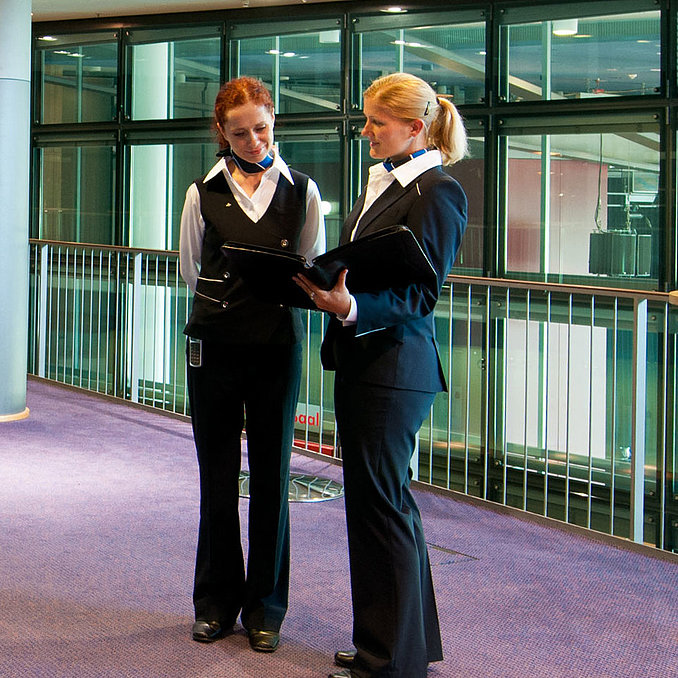 Foyer in Maritim Hotel Dresden with two staff members in uniform, standing tables, and a fruit station.