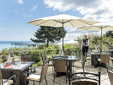 Restaurant terrace with sea view and sun umbrellas at Maritim Seehotel Timmendorfer Strand.