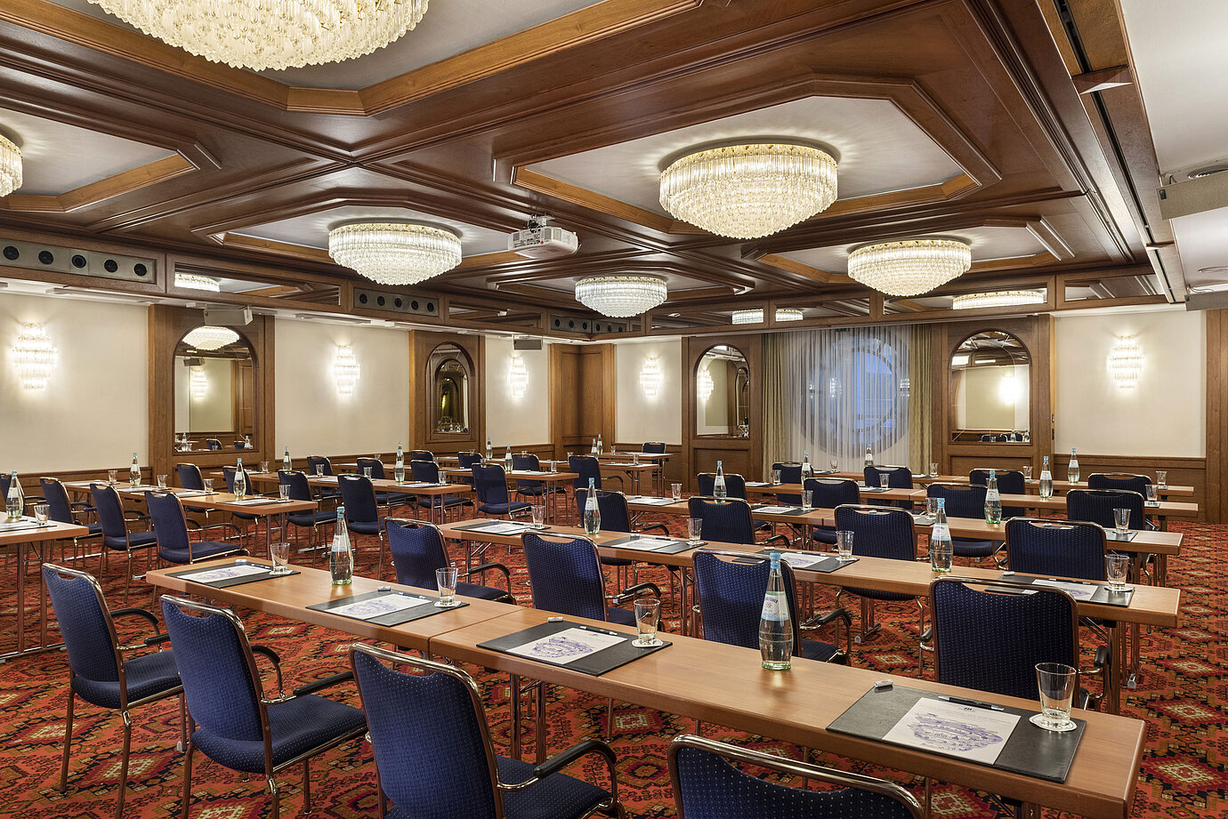 The Cologne Hall with elegant chandeliers and seating rows in a classic conference room setting, ready for a meeting.