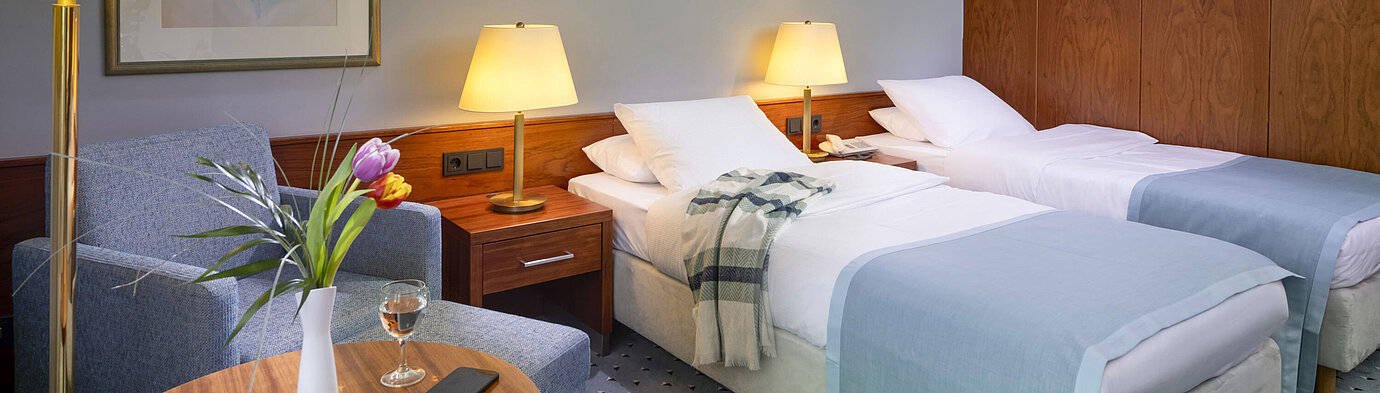 Comfort twin room at Maritim Hotel Darmstadt with two single beds, cozy seating area, and elegant interior design.