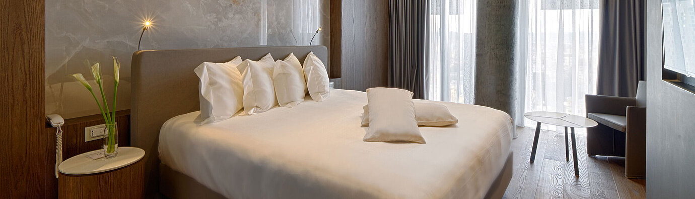 Quiet room with large bed, natural stone wall and soft curtains at Maritim Hotel Plaza Tirana