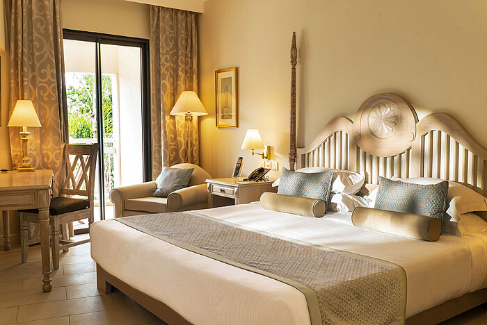 Suite with four-poster bed, seating area and open bathroom concept at Maritim Hotel