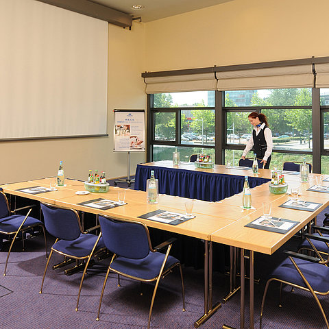 Meeting room in Maritim Hotel Dresden with U-shaped table setup, presentation screen, and meeting preparations.