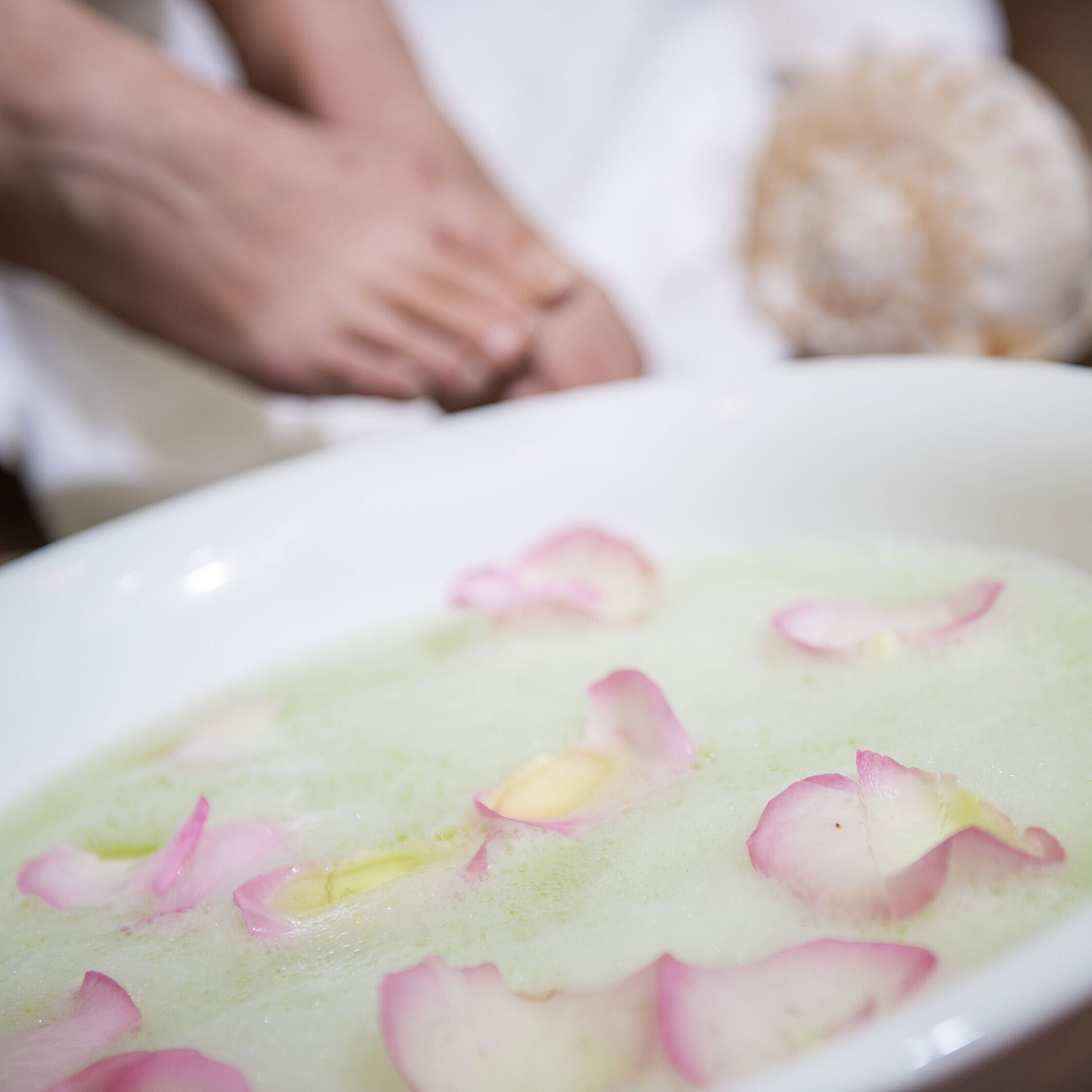 Foot bath with rose petals in a bowl during a spa treatment at the Maritim Hotel for soothing relaxation and care.