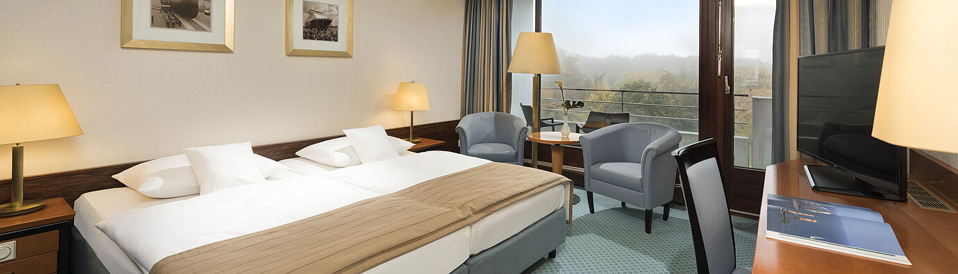 Classic room Classic room at the Maritim Hotel Kiel with large double bed, seating area, desk and balcony with a view of the countryside.