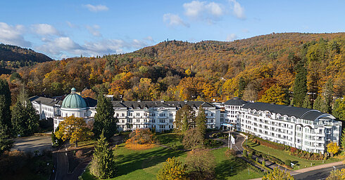 Exterior view of the Maritim Hotel Bad Wildungen surrounded by park, trees and an autumn forest panorama.