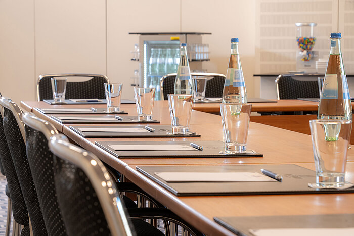 Set conference table at Maritim Hotel Bad Homburg with water, glasses and notepads.