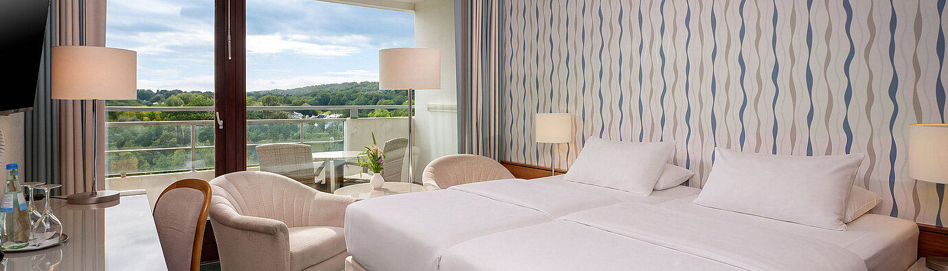 Classic Room with double bed, desk, armchair and large window overlooking the greenery