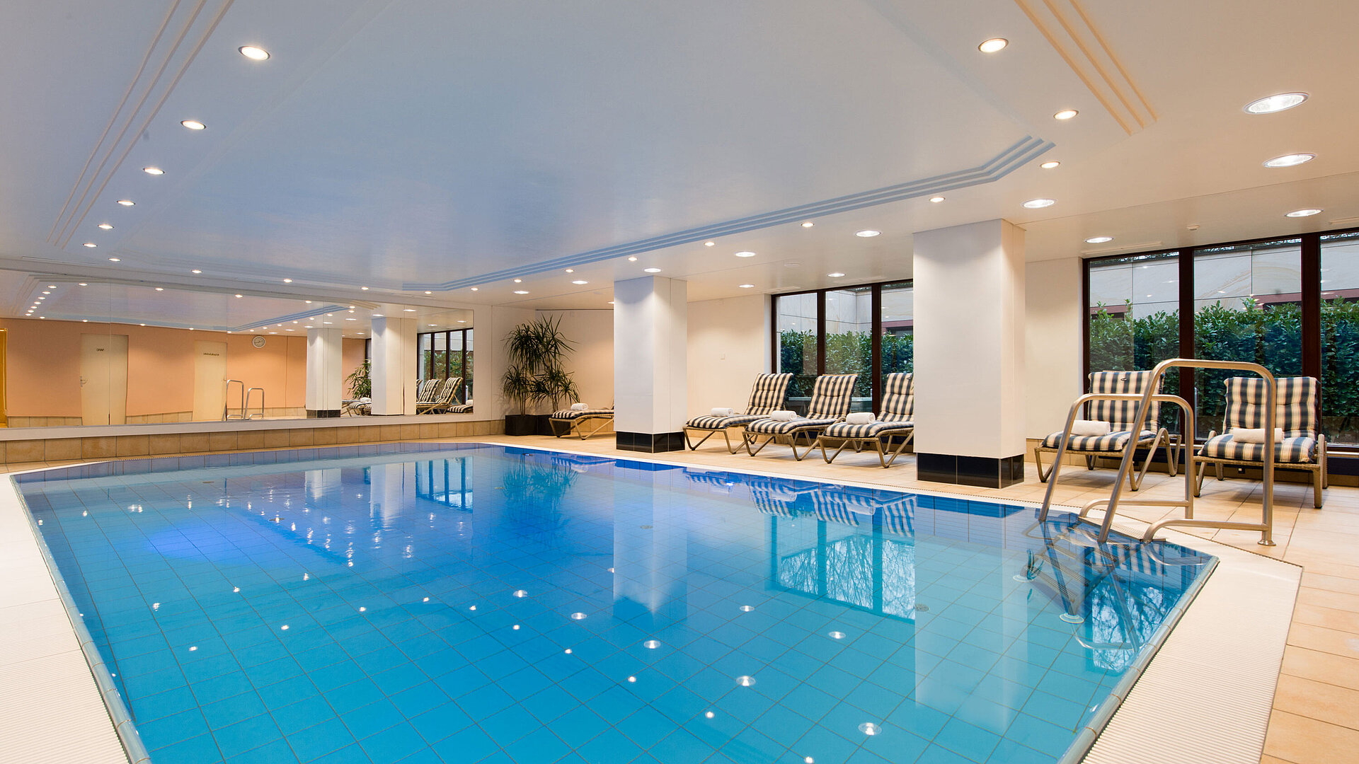 Pool Modern indoor pool at Maritim Hotel Fulda with lounge chairs, large windows, and a relaxing atmosphere.