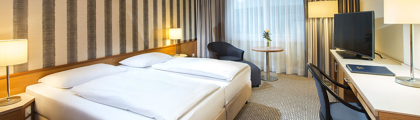 Modern double room with desk, TV and natural daylight at Maritim Hotel Stuttgart
