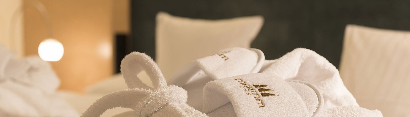 Bathrobe A fluffy bathrobe and slippers with Maritim logo on a bed at the Maritim proArte Hotel Berlin.
