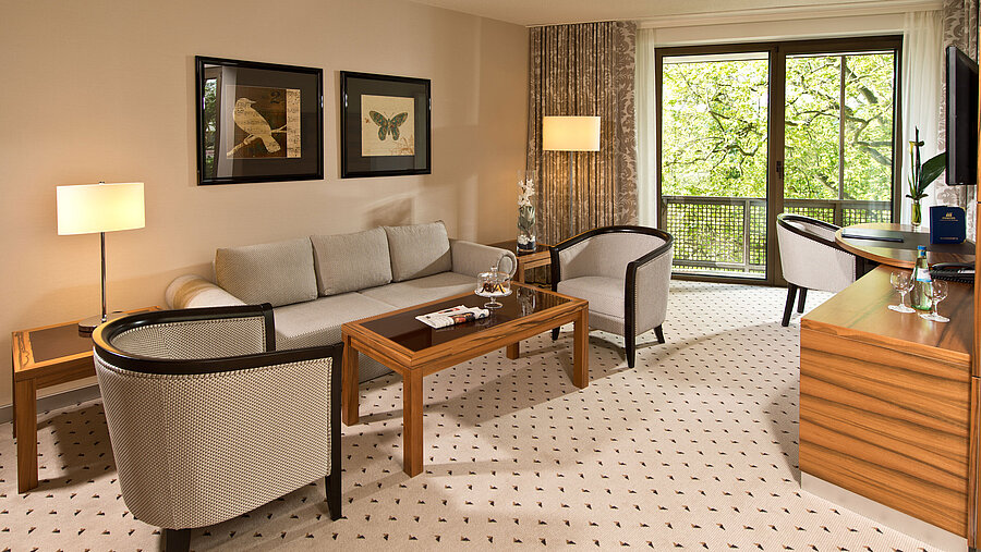 Cozy living area of the suite at Maritim Hotel Bad Homburg with elegant seating and balcony.