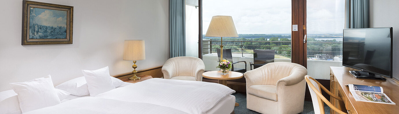 ComfortPlus room Double room with seating area, desk and balcony overlooking green landscape in Travemünde