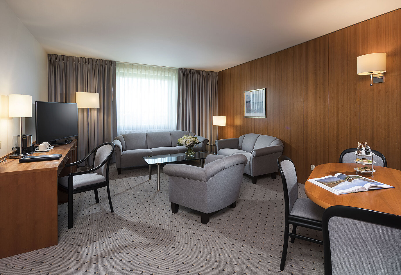 Junior Suite with elegant living area, sofa, armchairs, desk, and TV at Maritim Hotel Hannover.