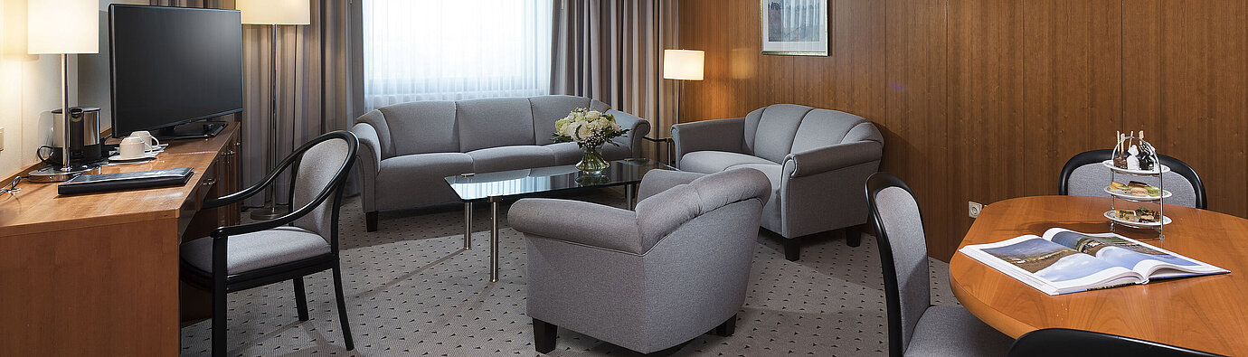 Junior suite  Junior Suite with elegant living area, sofa, armchairs, desk, and TV at Maritim Hotel Hannover.