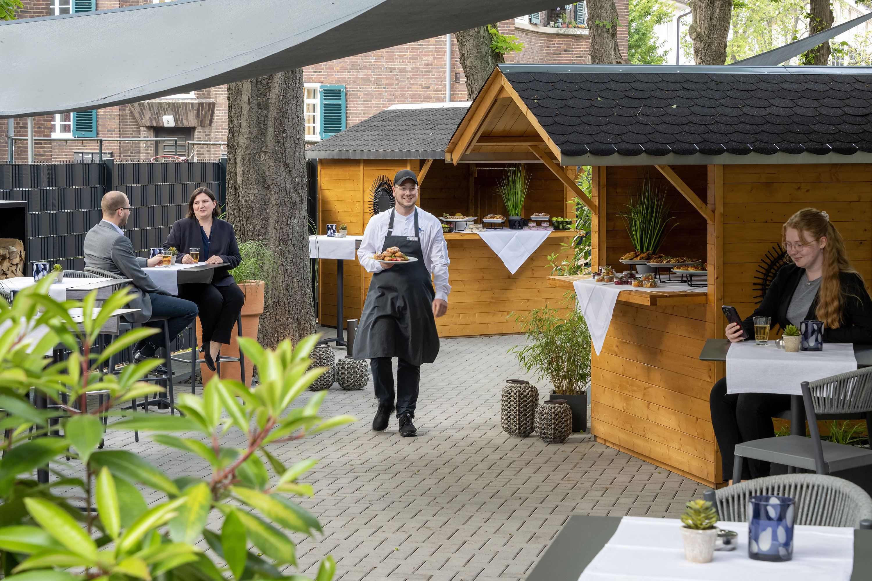 Outdoor terrace Waiter serving food at an event on the terrace of the Maritim Hotel Darmstadt with wooden huts